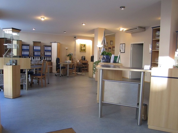 Modernes, freundlich eingerichtetes Büro mit Schreibtischen, Regalen und Aktenordnern.